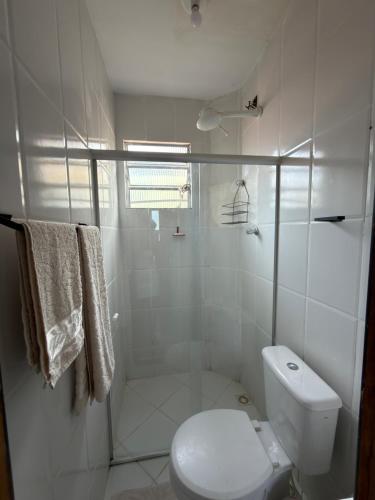 a white bathroom with a shower and a toilet at Espaço Parque das Gaivotas in Vila Velha