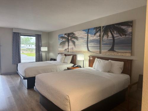 two beds in a hotel room with palm trees on the wall at Days Inn by Wyndham Lake City I-10 in Lake City