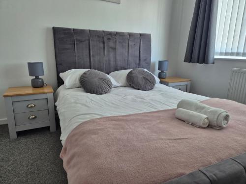 a bedroom with a bed with a headboard and two tables at Entire House - Cheshire Oaks/Ellesmere Port in Ellesmere Port