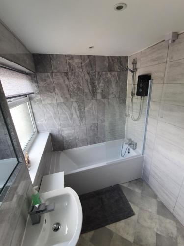 a bathroom with a tub and a toilet and a sink at Entire House - Cheshire Oaks/Ellesmere Port in Ellesmere Port