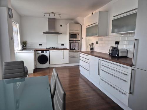 a kitchen with white appliances and a table in it at Entire House - Cheshire Oaks/Ellesmere Port in Ellesmere Port