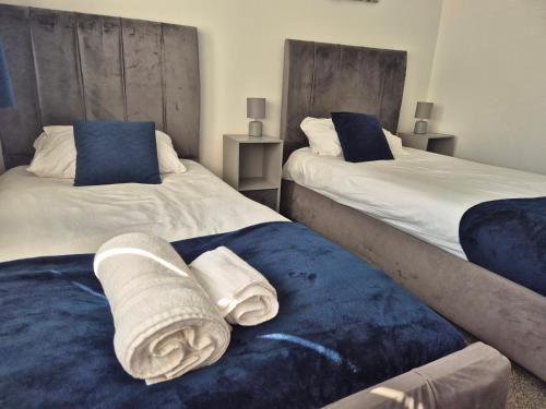 two beds with towels on them in a bedroom at Entire House - Cheshire Oaks/Ellesmere Port in Ellesmere Port