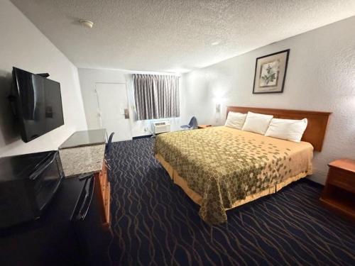 a hotel room with a bed and a flat screen tv at Crossroads Inn in Fort Pierce
