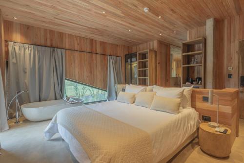 a bedroom with a large bed and a bath tub at Locus Solus Hotel Singular in Mar del Plata