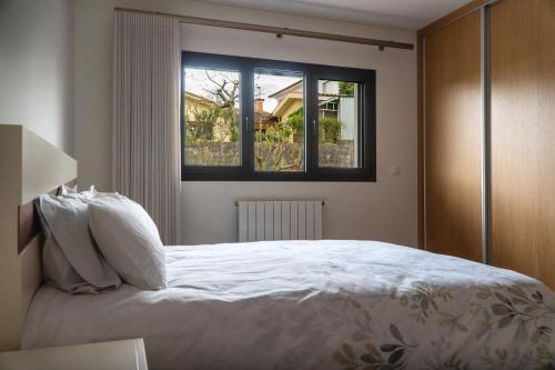 a bedroom with a white bed with a window at Casa do Paçô - Cabeceiras de Basto in Cabeceiras de Basto