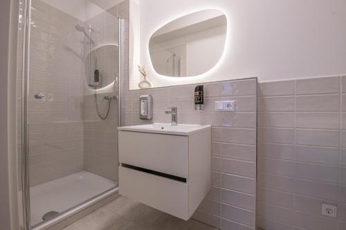 a white bathroom with a sink and a shower at Altstadt City Loft in Würzburg