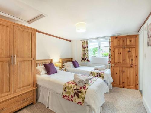 two beds in a room with wooden cabinets at 3 Bed in Wareham oc-dc129 in Turners Puddle