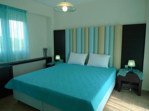 a bedroom with a blue bed and two lamps at Excellent Villa in Vourvourou