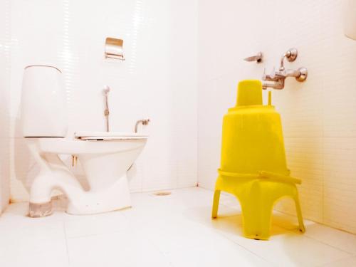 a bathroom with a toilet and a yellow stool at Hotel Sanskar in Pachmarhī