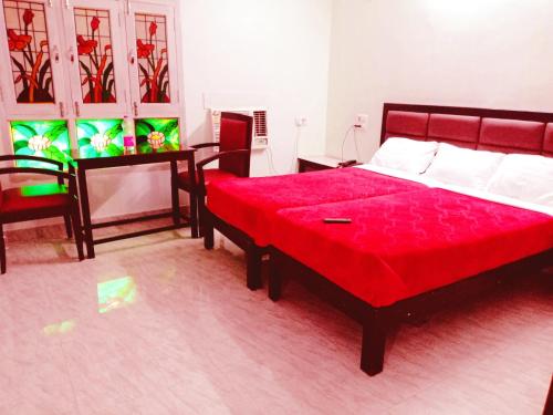 a bedroom with a large red bed and a table at Hotel Sanskar in Pachmarhī