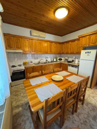 a kitchen with a wooden table and a white refrigerator at Pansedon House by the sea in Nea Kallikrateia