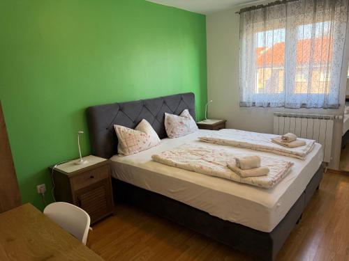 a bedroom with a large bed with green walls at Apartments Amela in Pula