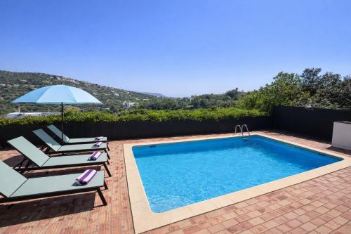 a swimming pool with two chairs and an umbrella at Casa da Parreira in Loulé