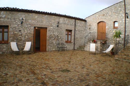 a courtyard of a stone building with white chairs at Il Baglio di Nonna Clelia in Polizzi Generosa