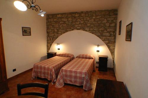 a bedroom with two beds and a stone wall at Il Baglio di Nonna Clelia in Polizzi Generosa