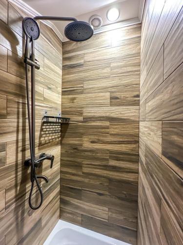 a bathroom with a tub and a shower with wooden walls at Шале in Krivopolʼye