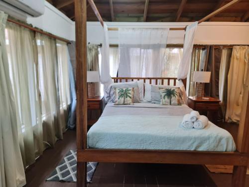 a bedroom with a canopy bed with towels on it at Las Palmas Beach Roatan in Dixon Cove