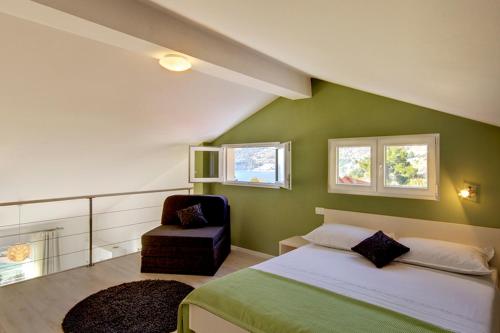 een groene slaapkamer met een bed en een stoel bij Apartments Lianto in Drasnice