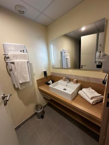 a bathroom with a sink and a large mirror at Brit Hotel Montargis in Mormant-sur-Vernisson