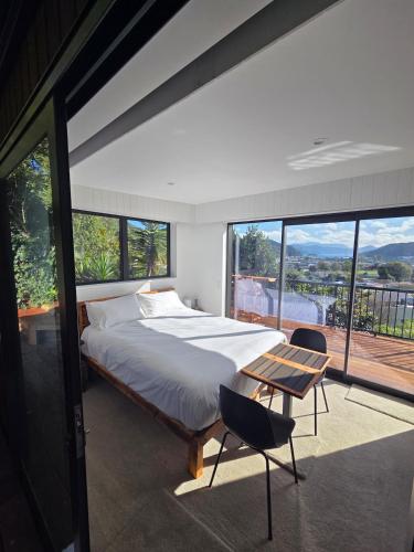 a bedroom with a bed and a table and windows at The Landing - Picton in Picton