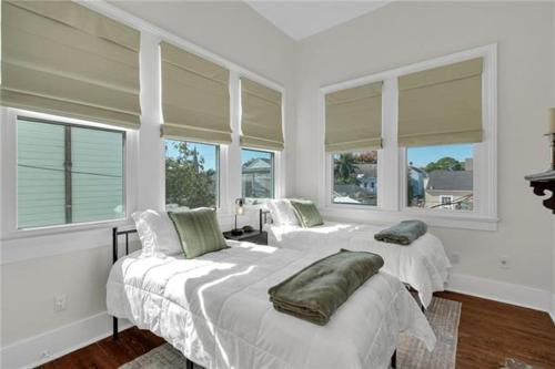 two beds in a white room with windows at Prytania Pearl - 3 Bedroom 2 Bathroom Home in New Orleans