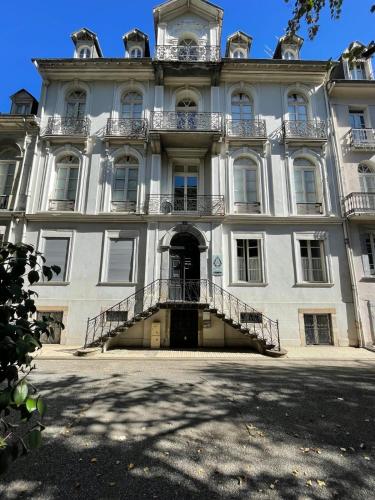 a large white building with stairs in front of it at App T2 avec piscine chauffée in Luchon