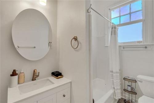 a white bathroom with a shower and a mirror at Prytania Pearl - 3 Bedroom 2 Bathroom Home in New Orleans
