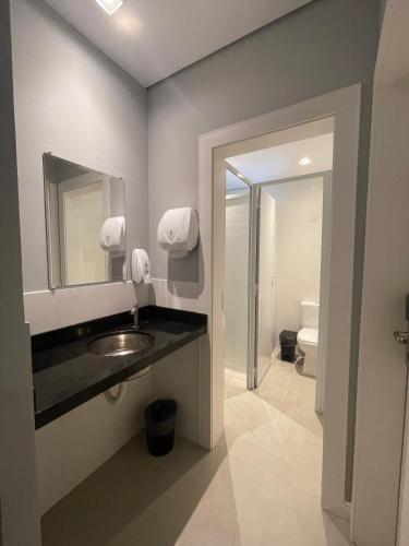 a bathroom with a sink and a mirror and a toilet at Social Hostel Café e Bar in Curitiba
