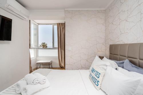 a bedroom with a white bed and a window at The View II Costa Caparica ( private parking ) in Costa da Caparica