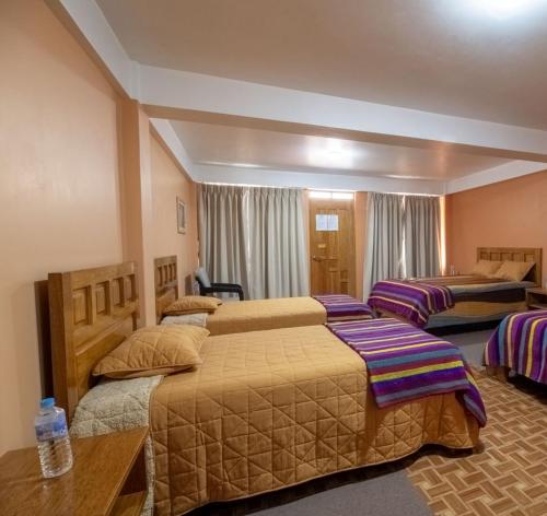 a hotel room with two beds and a table at La Chacana Hotel Boutique in Huaraz