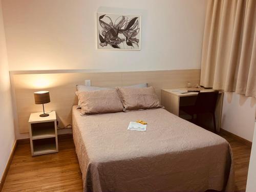 a small bedroom with a bed and a desk at Flat Lagoa Santa in Lagoa Santa
