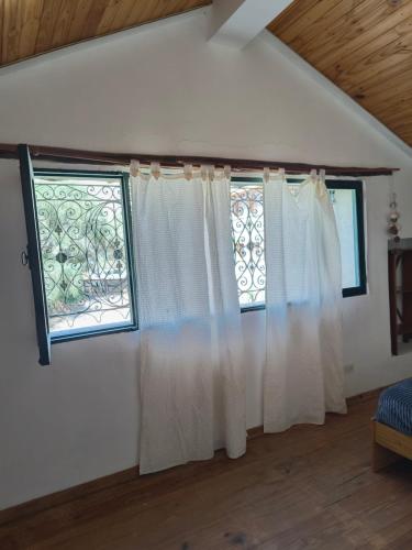 two windows with white curtains in a room at Cabaña Padilla in Tilcara