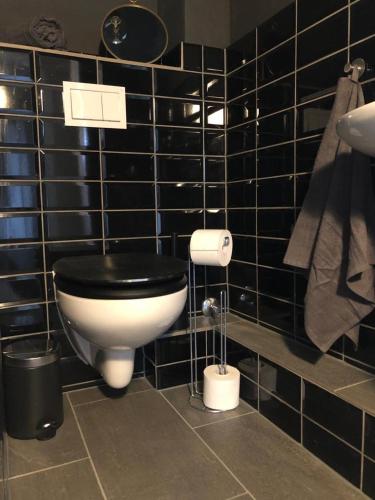 a black tiled bathroom with a toilet with a black seat at Justs Place in Garding