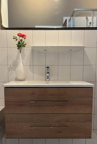 a bathroom with a vase with a red rose in it at Hannas Place in Garding