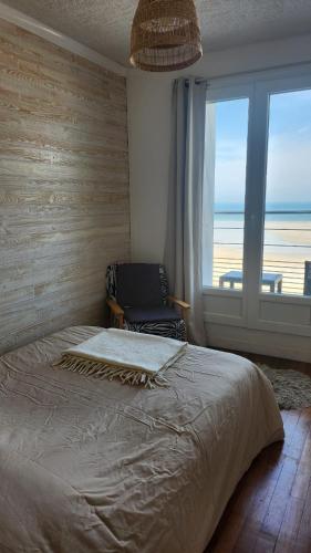 a bedroom with a bed and a chair and a window at Chambre avec vue sur mer in Saint Malo