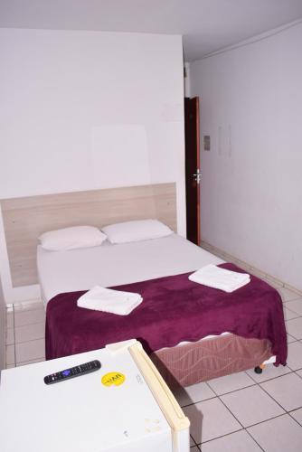 a bedroom with a bed with a remote control on it at Hotel Imperador Caldas Novas - GO - Facil acesso aos parques aquaticos e polo gastronômico noturno in Caldas Novas