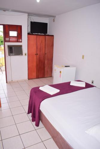 a bedroom with a bed with a purple blanket at Hotel Imperador Caldas Novas - GO - Facil acesso aos parques aquaticos e polo gastronômico noturno in Caldas Novas