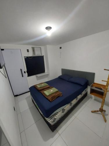 a small bedroom with a blue bed and a flat screen tv at Pousada Caverna da Praia in Rio de Janeiro
