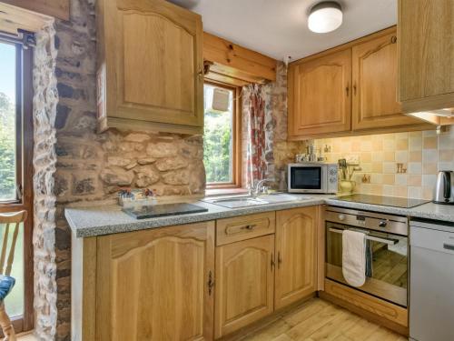 a kitchen with wooden cabinets and a stone wall at Allerford- Ukc4920 in Timberscombe