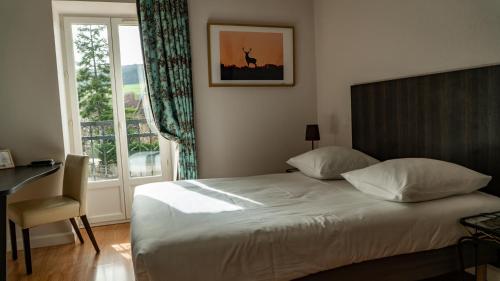 a bedroom with a bed and a desk and a window at Logis Hôtel L'Orée des Charmes et son restaurant L'évYdenCe in Blaisy-Bas