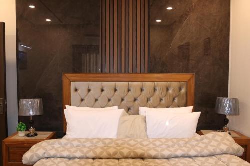 a bedroom with a large bed with white pillows at Designer Den two Bed apartment opposite to giga mall in Islamabad