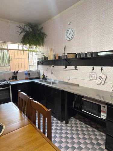 a kitchen with a sink and a table and a clock at Sobrado versátil in Santo André