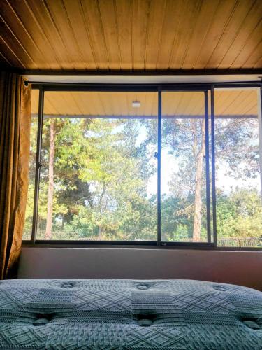 a bedroom with a large window with a bed in front of it at Volterra Guatavita in Guatavita