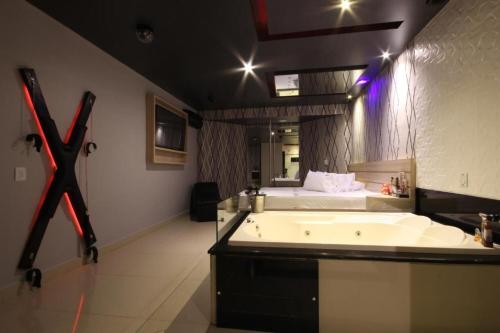 a large bathroom with a tub and a bed at Motel Deslize Limeira 4 in Limeira