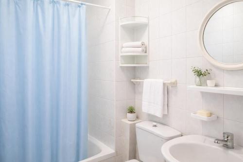 a bathroom with a shower curtain and a toilet and a sink at Pensión Rey in Isla de Arosa