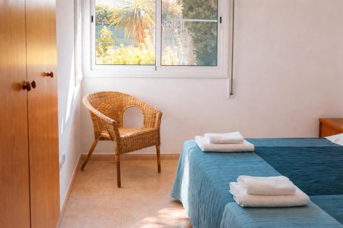 a bedroom with a bed and a chair and a window at Casa Amor - "Pet Friendly - Piscina Privada - Playa - BBQ - Parking - Delta de l'Ebre - Riumar" in Riumar