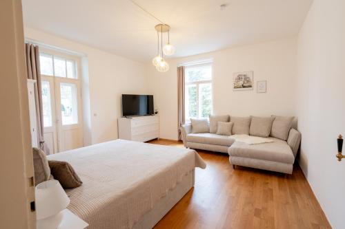 a white bedroom with a bed and a couch at Stadtvilla Alpenliebe in Bad Reichenhall