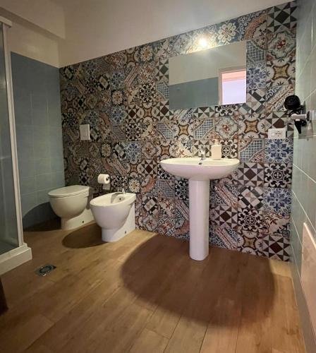 a bathroom with a sink and a toilet and a mirror at Roccazzo 16 in Cefalù