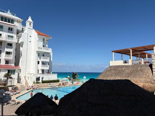 a swimming pool next to a building and the ocean at Cancun Plaza - Best Beach in Cancún