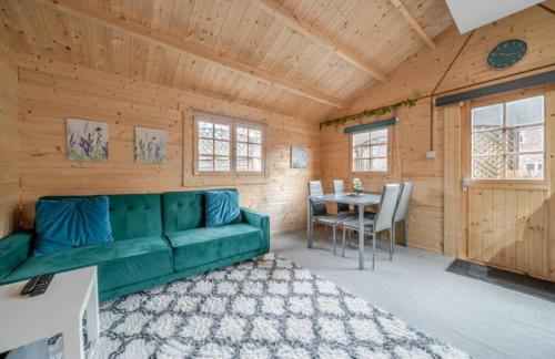 a living room with a green couch and a table at The Cosy Cabin in Old Windsor